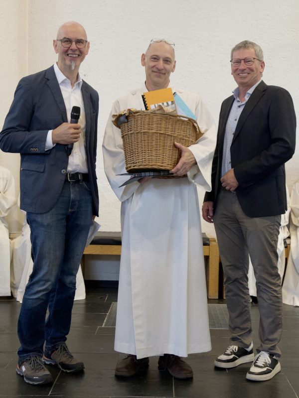 Das Bild zeigt Gundolf Zahn mit überreichtem Geschenkkorb, Links und rechts neben ihm stehen zwei Männer.