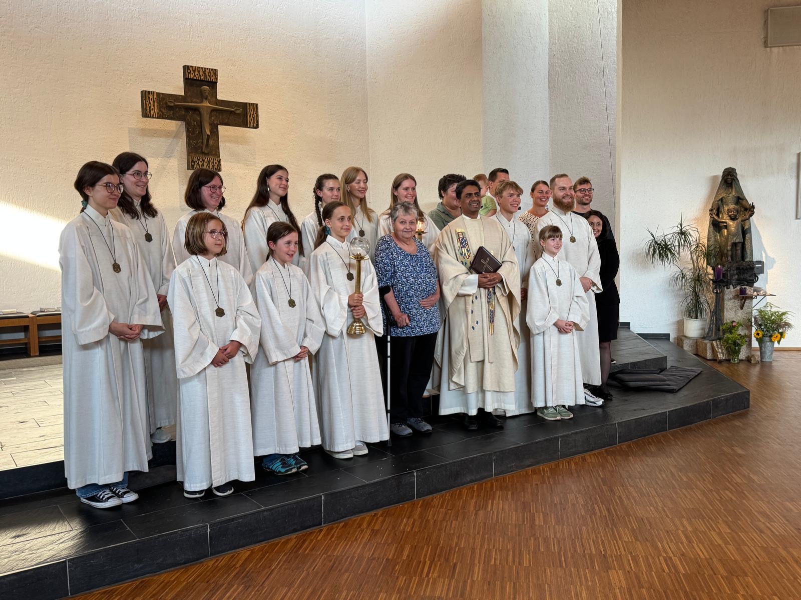 Das Bild zeigt Uschi Miller neben Pfarrer George und umrahmt von vielen Ministrantinnen und Ministranten